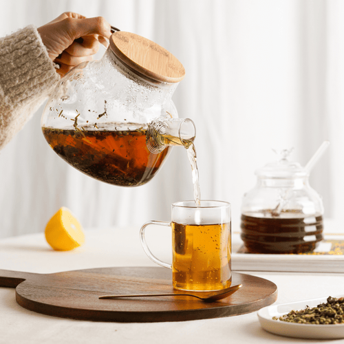 Tee wird aus der Ölich Glaskanne in ein Teeglas gegossen